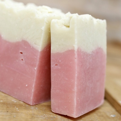 Sabonete artesanal branco e rosa sobre tábua de madeira
