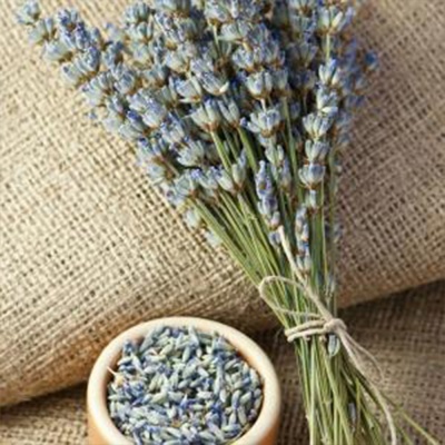 ramo de alfazema seca e recipiente com alfazema sobre tecido de juta