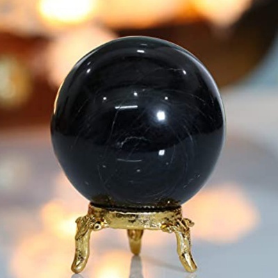 Esfera negra polida sobre suporte dourado em fundo desfocado