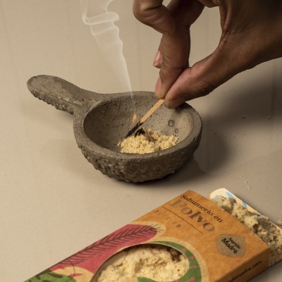 Almofariz cinza com pó e fósforo aceso, embalagem de sahumerio em pó