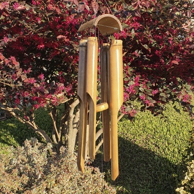 Sino dos ventos de bambu pendurado em árvore com folhas castanhas vermelhas em jardim