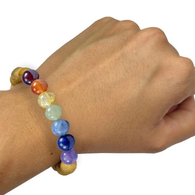 Bracelete colorida de contas esféricas de pedras e madeira num pulso com pele clara