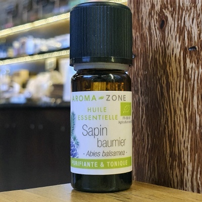 Frasco pequeno de óleo essencial verde e branco sobre madeira com fundo desfocado