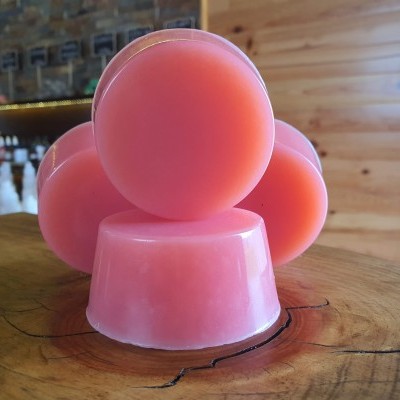 Sabonetes sólidos cor-de-rosa empilhados sobre madeira com fundo de parede e prateleiras