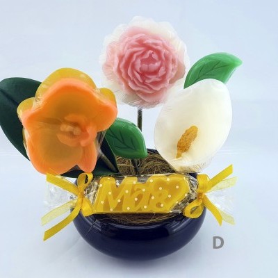 Arranjo decorativo com flores coloridas e base preta com rótulo amarelo 'Mãe'.