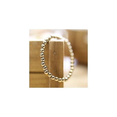 Pulseira de esferas metálicas prateadas sobre madeira clara