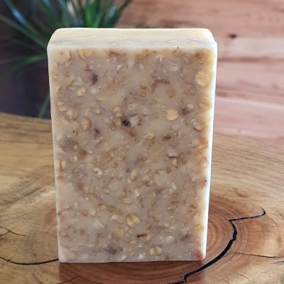 Sabonete retangular artesanal bege com textura de aveia em madeira rústica