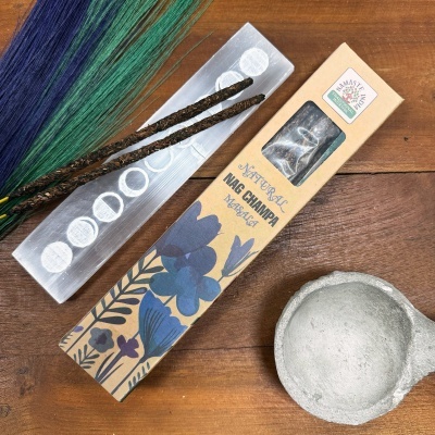 Duvas varetas de incenso e embalagem Natural Nag Champa com recipiente cinza sobre mesa de madeira