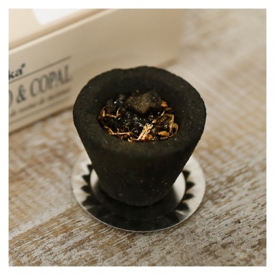 Incenso preto em cone com resina em suporte metálico sobre mesa de madeira