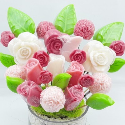 Arranjo decorativo com rosas brancas, rosas e folhas verdes num vaso transparente