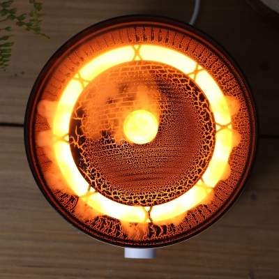 Lâmpada redonda decorativa iluminada com textura e cores laranja e amarelo em cima de superfície de madeira