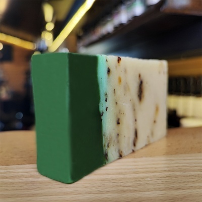 Sabonete retangular verde e branco sobre superfície de madeira num interior desfocado