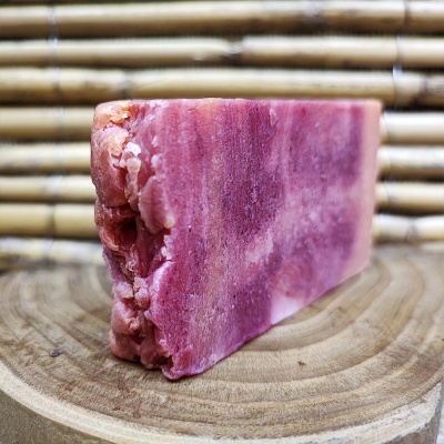 Sabonete artesanal rosa e vermelho sobre base de madeira com fundo de bambu