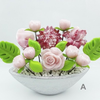 Arranjo artificial de flores rosa, folhas verdes e vaso branco com pedras