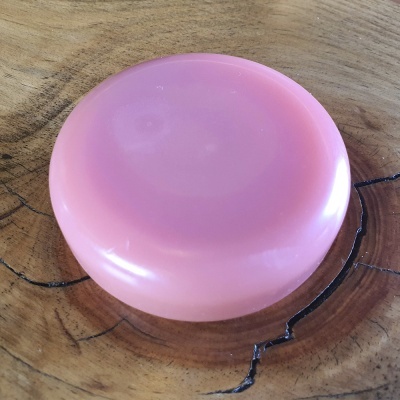 Sabonete redondo cor-de-rosa sobre madeira com veios