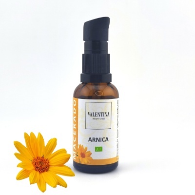 Frasco de óleo de Arnica Valentina Body Care com uma flor amarela