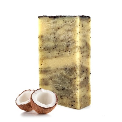 Barra de sabão retangular com textura granulada e pedaços de coco partido ao meio