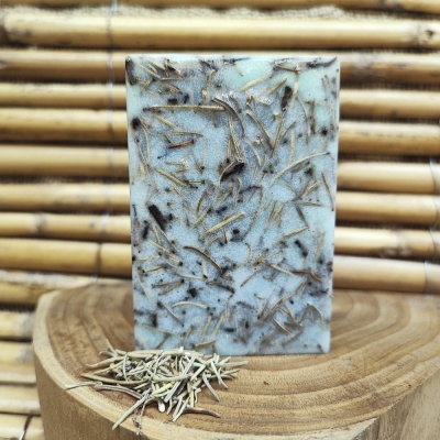 Sabonete artesanal com ervas secas sobre prato de madeira