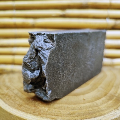 Bloco de carvão vegetal cinzento-escuro sobre superfície de madeira com fundo de bambu