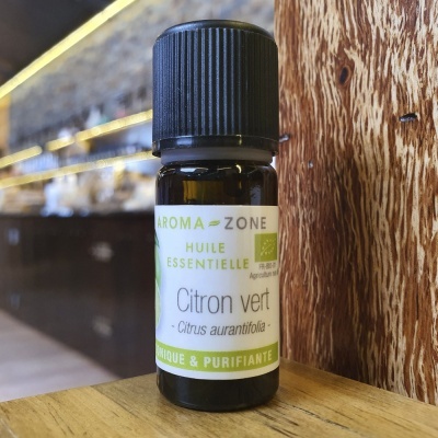 Frasco de óleo essencial de Citron vert AROMA ZONE sobre superfície de madeira