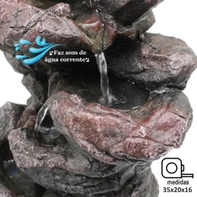 Fonte decorativa de pedras em castanho e cinzento com água a correr e texto em português