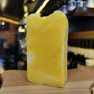 Barra de sabão amarela com textura irregular em tábua de madeira