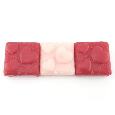 Três caixas quadradas decorativas vermelhas e rosa com corações em relevo