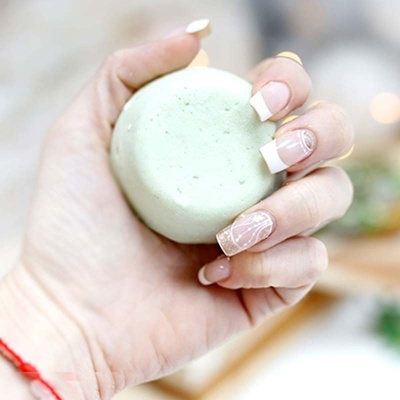 Mão com unhas decoradas a segurar bola esponjosa verde