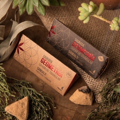 Dois pacotes de incenso triangular com design geométrico em ambiente rústico com plantas e resina