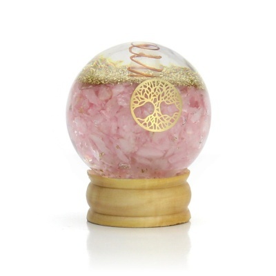 Globo decorativo com cristais rosa, espiral metálica e pendente dourado sobre base de madeira