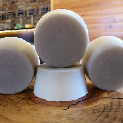 Sabonetes redondos cinza claros sobre superfície de madeira clara.