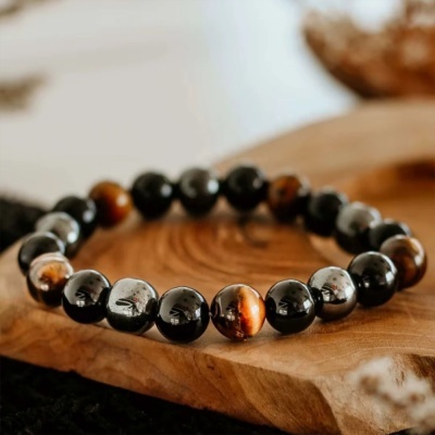 Pulseira de bolas polidas pretas, cinzentas e castanhas sobre madeira clara