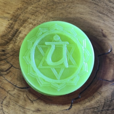 Sabonete redondo verde com símbolo esculpido colocado sobre superfície de madeira