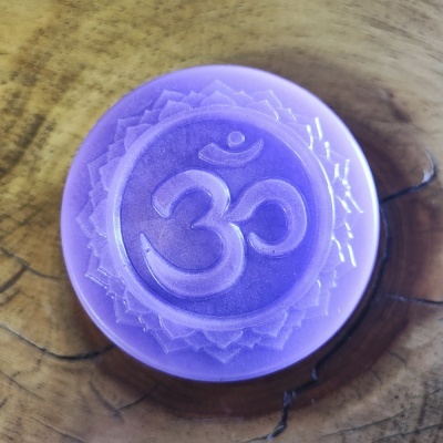 Disco redondo violeta com símbolo Om gravado sobre madeira