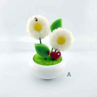 Figuras decorativas de flores brancas, folhas verdes e animais pequenos numa base branca.