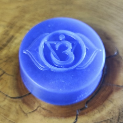 Vela redonda azul com símbolo gravado sobre madeira clara