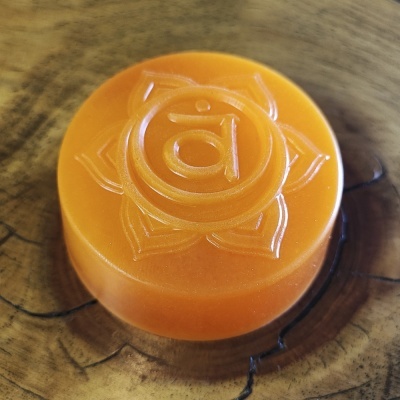 Sabonete redondo laranja com símbolo em relevo sobre madeira