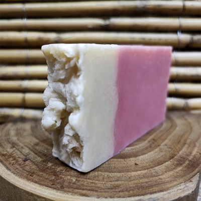 Sabonete artesanal bicolor branco e rosa sobre madeira com fundo de bambu