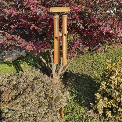 Sino dos ventos de madeira pendurado em árvore com folhas roxas