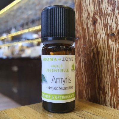 Frasco pequeno de óleo essencial Amyris da marca Aroma Zone sobre superfície de madeira