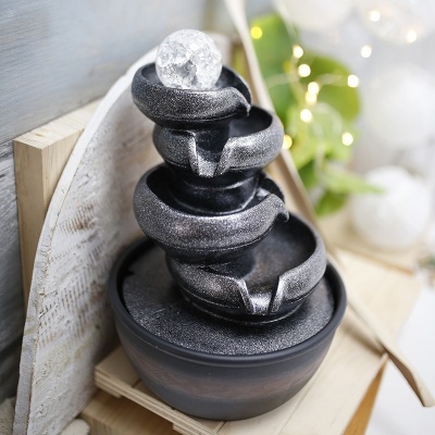 Fonte decorativa preta em cascata com esfera de vidro no topo sobre base redonda