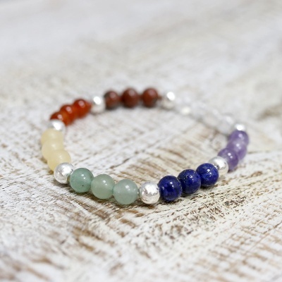 Pulseira com contas coloridas e metálicas sobre fundo branco texturizado