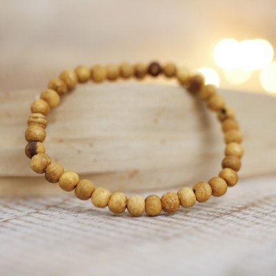 Pulseira de contas de madeira castanhas claras sobre superfície de tecido e madeira clara