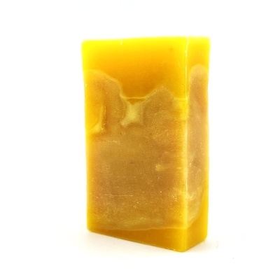 Barra de sabão amarela sólida com textura irregular sobre fundo branco