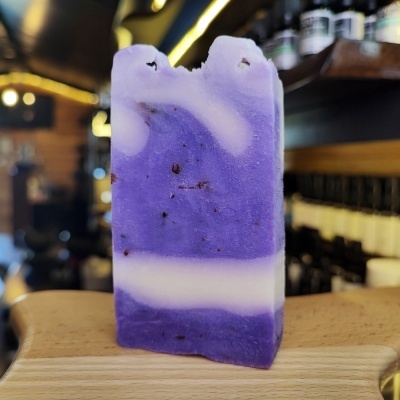 Sabonete artesanal roxo e branco sobre suporte de madeira