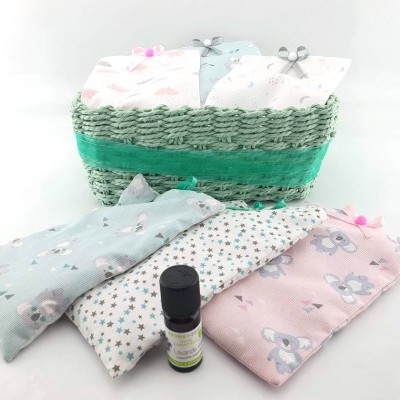 Cesto verde com saquinhos de tecido rosa, azul claro e branco decorados e frasco pequeno