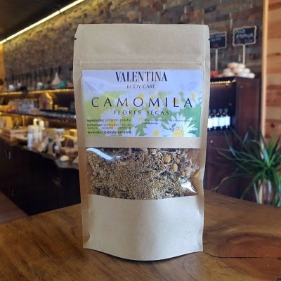 Embalagem de flores secas de camomila com rótulo VALENTINA BODY CARE em ambiente interno