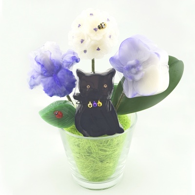 Arranjo decorativo com flores artificiais e gato negro em copo de vidro