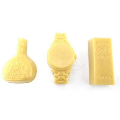 Três objetos amarelos: garrafa com 'WHISKY', relógio de pulso e barra com 'Fine Gold 999.9 1000 g'