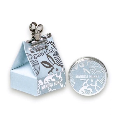 Embalagem e frasco de mel Manuka azul claro com padrão floral e texto